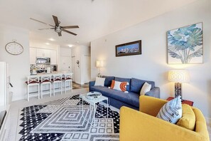 Ein modernes Wohnzimmer mit einer Couch, einem gelben Sessel und einem gemusterten Teppich.