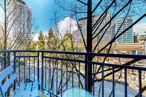Ein Balkon mit Metallgeländer, der auf einen Parkplatz und Gebäude im Hintergrund blickt.