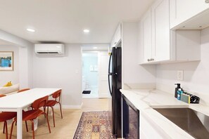 Eine moderne Küche mit weißen Schränken, einem schwarzen Kühlschrank und einer Marmorarbeitsplatte.