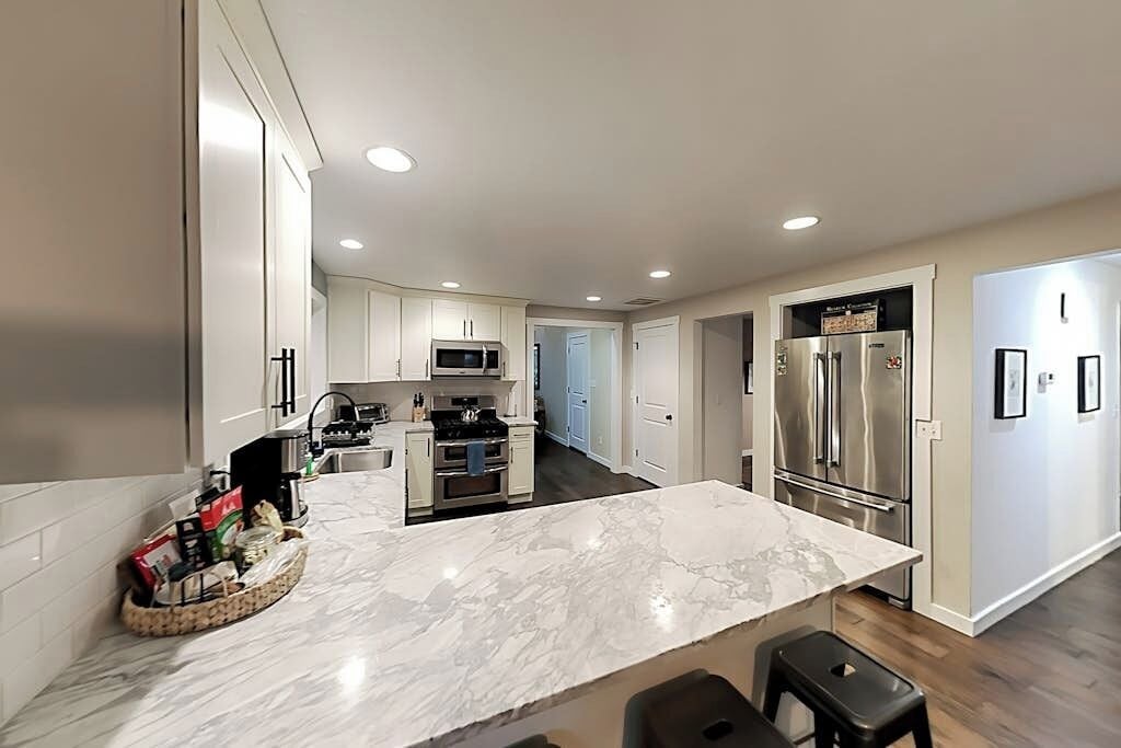 A modern kitchen with a marble countertop, stainless steel appliances, and a central island.
