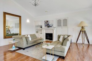 Ein Wohnzimmer mit Kamin, zwei Sofas, einem Couchtisch und einer Stehlampe.