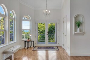 A spacious room with a large window, a bench, and a chandelier. - 3BR water-view home with fireplace, deck, tub, Washer Dryer (Blaine)