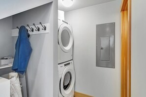 A laundry room with stacked washing machines, a drying rack, and a utility panel. - Amazing 2BR Soundview - Deck - Washer Dryer (Kingston)