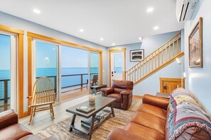 A spacious living area with a view of the sea, a wooden staircase, and a leather sofa. - Amazing 2BR Soundview - Deck - Washer Dryer (Kingston)