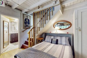 Ein Schlafzimmer mit einem Bett, einer Holztreppe, einem kleinen Tisch und einem Spiegel.
