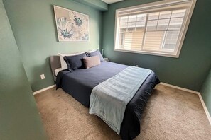 A bedroom with a bed, a window, and a wall-mounted artwork. - Corner 3BR - Fireplace - Balcony - Washer Dryer (Seattle)