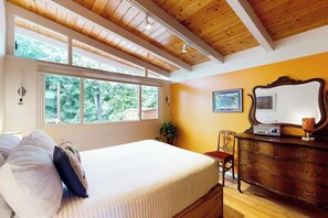 A bedroom with a bed, a dresser, a chair, and a window with a view of trees. - 1BR Home- Tranquil Mid-Century retreat (Seattle)