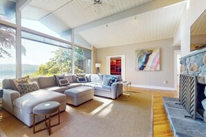 Ein geräumiges Wohnzimmer mit Ecksofa, Hocker und Kamin.