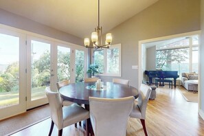 A dining area with a round table, chairs, and a chandelier. - 2BR Lakefront home with deck & garage parking (Lake Forest Park)