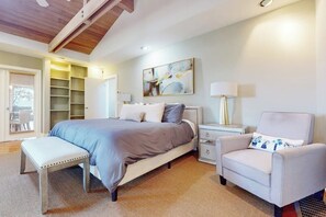 Une chambre à coucher avec un lit, des tables de chevet, un banc, une chaise et un tableau au mur.
