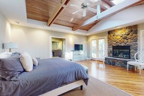 A bedroom with a bed, a stone fireplace, a television, and a dining area. - 2BR Lakefront home with deck & garage parking (Lake Forest Park)