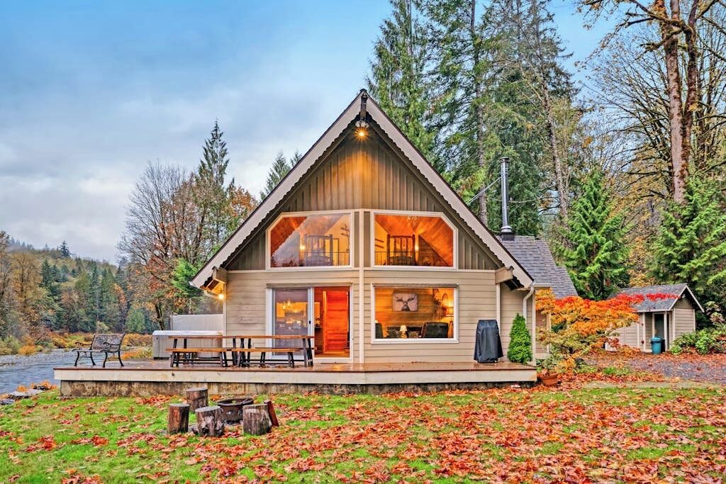 A cabin with a large deck, a fireplace, and a view of the forest.