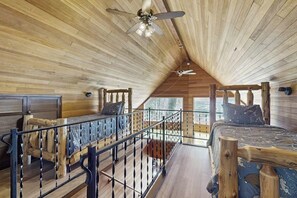 A cabin interior with a loft bedroom, a balcony with a railing, and a ceiling fan. - Upgraded 3BR Riverfront - Hot Tub - WoodStove (Sultan)