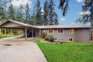 A two-story house with a covered porch, a well-maintained lawn, and tall trees in the background. - 3BR Secluded home near downtown Washer Dryereck & grill (Woodinville)