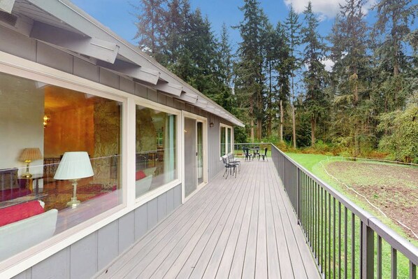 A wooden deck with outdoor furniture, overlooking a forested area. - 3BR Secluded home near downtown Washer Dryereck & grill (Woodinville)