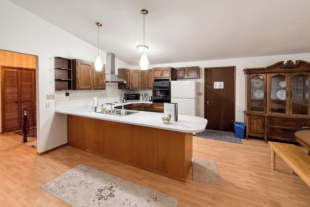 A modern kitchen with wooden cabinets, a central island, and a built-in oven.