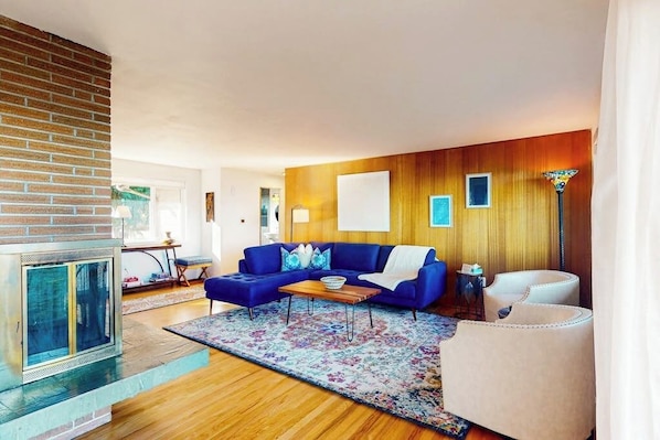 A living room with a sectional sofa, a coffee table, a fireplace, and a patterned rug. - 2BR Vashon Island Home with Breathtaking views (Vashon)