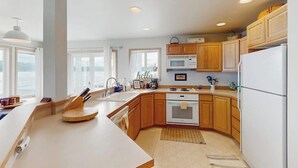 Una cocina moderna con armarios de madera, un refrigerador blanco y un ventanal grande.