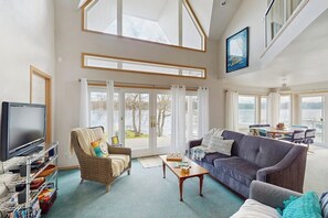 Ein geräumiges Wohnzimmer mit großem Fenster, Fernseher, Sofa und Couchtisch.