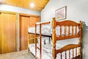 Ein Etagenbett mit Holz Kopfteil, ein Holzschrank und ein gerahmtes Bild an der Wand.