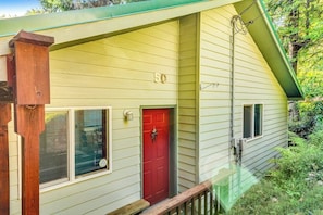 Une maison de plain-pied avec une porte rouge, une boîte aux lettres et le numéro « 50 » peint sur le mur.