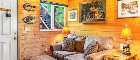 A cozy cabin interior with a wooden interior, a sofa, a coffee table, and a lamp.