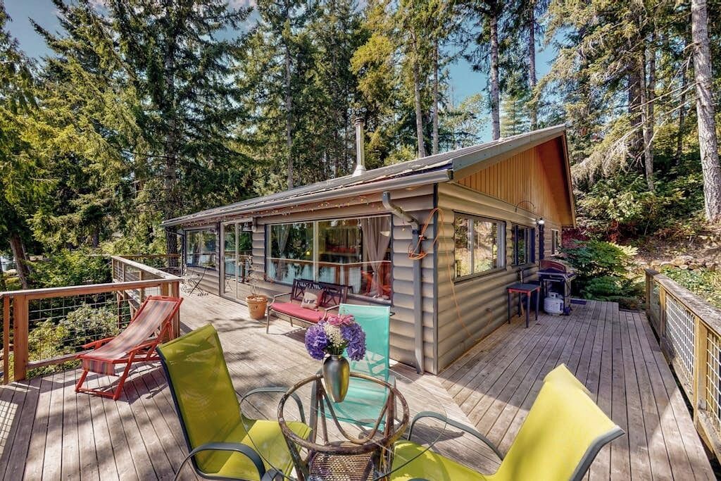 Een chalet met een terras, buitenmeubels en uitzicht op het bos.