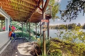 A covered outdoor area with a wooden structure, a dock extending into a lake, and a view of a forested landscape.