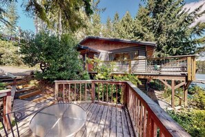 A cabin with a deck, a hot tub, and a view of a lake surrounded by trees. - Fantastic 2BR Lakefront - Dock - Fireplace (Grapeview)