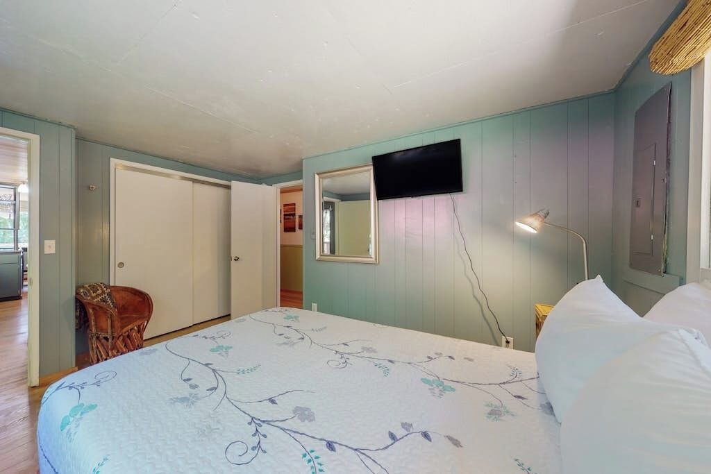A bedroom with a bed, a television mounted on the wall, and a chair.