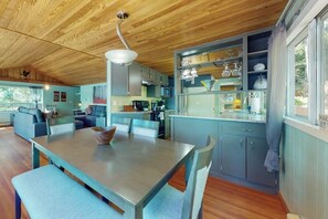 A modern kitchen with wooden ceiling, a dining table with chairs, and a view of the outdoors. - Fantastic 2BR Lakefront - Dock - Fireplace (Grapeview)