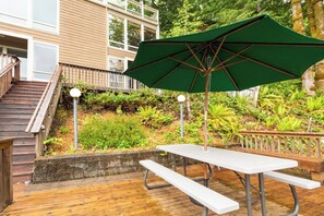 A wooden deck with a picnic table and a green umbrella.