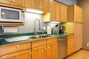 A kitchen with wooden cabinets, a stainless steel sink, a microwave, and a dishwasher.