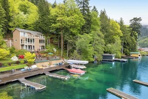 A lakeside property with a dock, boats, and a building with a deck.
