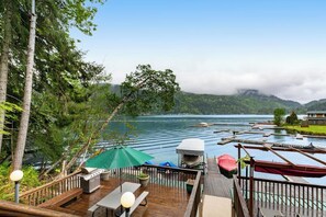 A deck with outdoor seating, a grill, and a view of a lake with boats.