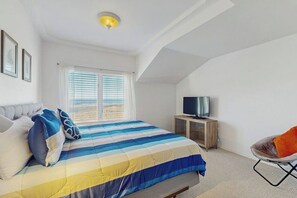 Ein Schlafzimmer mit einem Bett, einem Fernseher auf einer Holzkommode und einem Sessel.