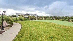 Een golfbaan met een verzorgd gazon, een pad en een gebouw op de achtergrond.
