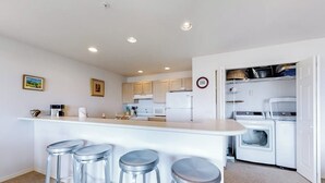 Een moderne keuken met een centraal eiland, barstoelen en inbouwapparatuur.