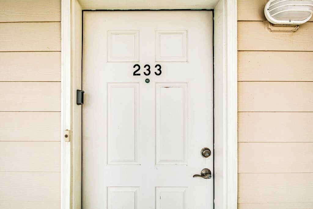 A white door with the number 233, a doorknob, and a small light fixture above it.