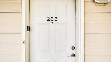 A white door with the number 233, a doorknob, and a small light fixture above it.