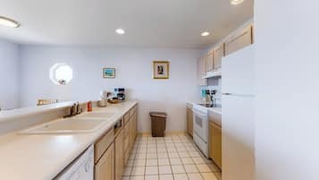A compact kitchen with a dishwasher, a sink, and a trash bin.