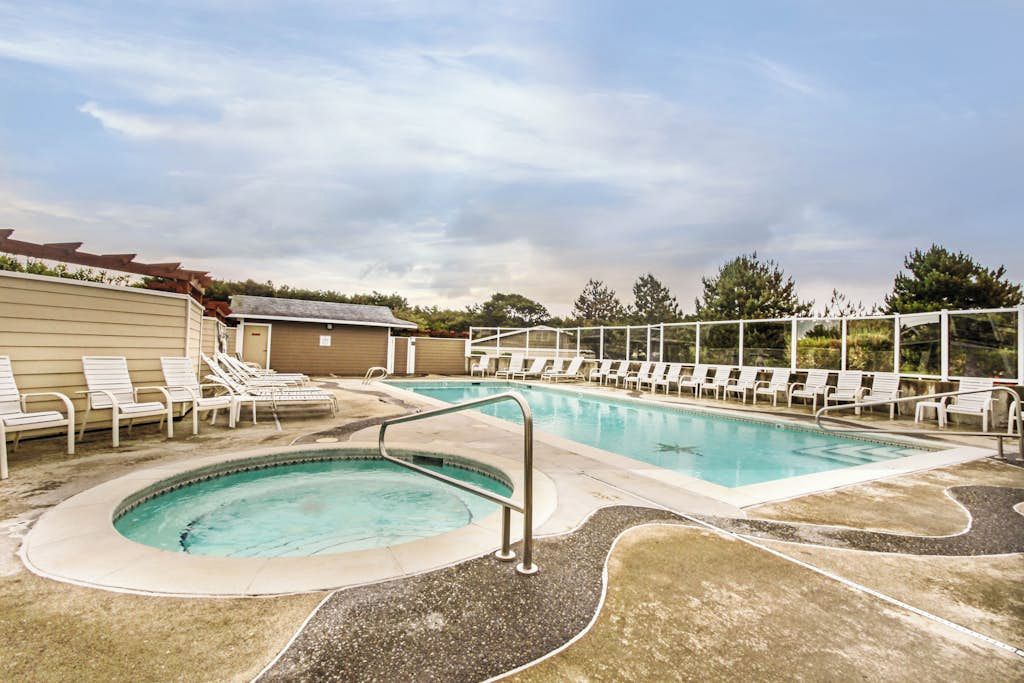 A swimming pool with lounge chairs and a small hot tub area.