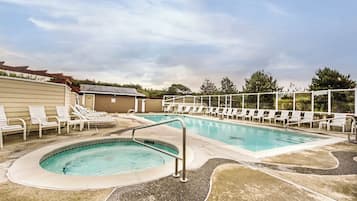 A swimming pool with lounge chairs and a small hot tub area.