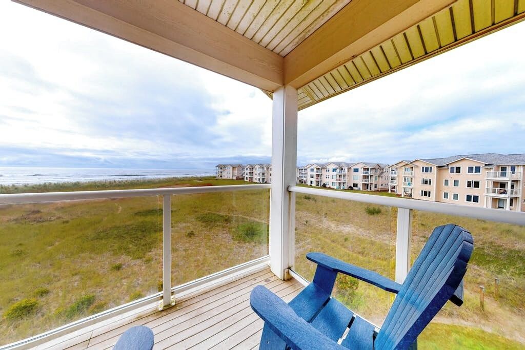 A covered outdoor area with a view of a beach and residential buildings.