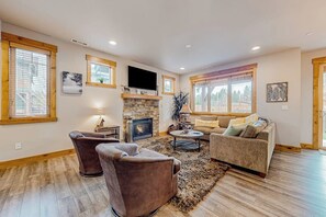 A living room with a fireplace, a flat-screen TV, and a sofa. - BlackBearLodge 4BR with ensuites - walk everywhere (Cle Elum)