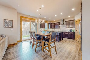 A spacious kitchen with a dining area, wooden flooring, and a large window. - BlackBearLodge 4BR with ensuites - walk everywhere (Cle Elum)