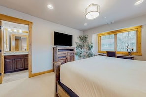 A bedroom with a large bed, a TV, a wooden dresser, and a window with blinds. - BlackBearLodge 4BR with ensuites - walk everywhere (Cle Elum)