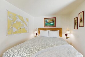A hotel room with a large bed, a map on the wall, and two wall-mounted lamps. - 1BR Home great for work, play, easy Seattle access (Bainbridge Island)