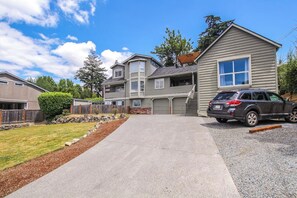 Un quartier résidentiel avec une maison à deux étages, une allée et une voiture garée.