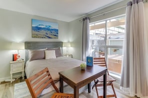 Une chambre à coucher comprenant un lit, des tables de chevet, un bureau, des chaises, une fenêtre avec des rideaux et un tableau accroché au mur.